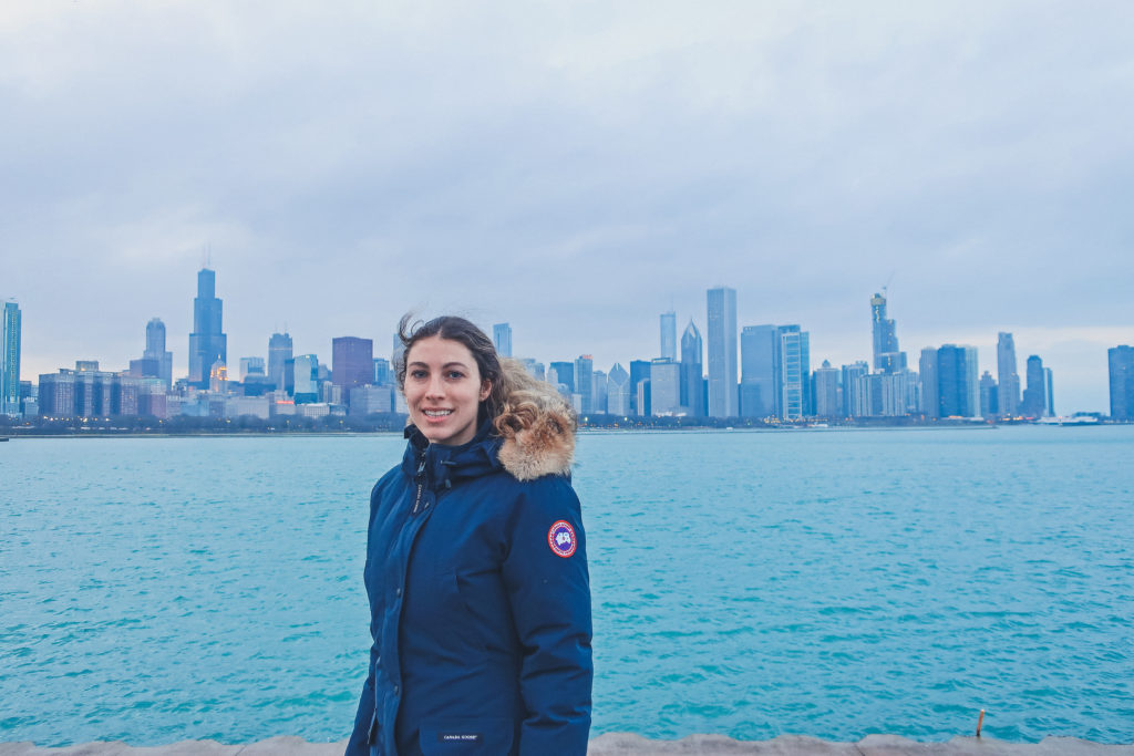 woman stands near Planetarium in Chicago, skyline behind her 