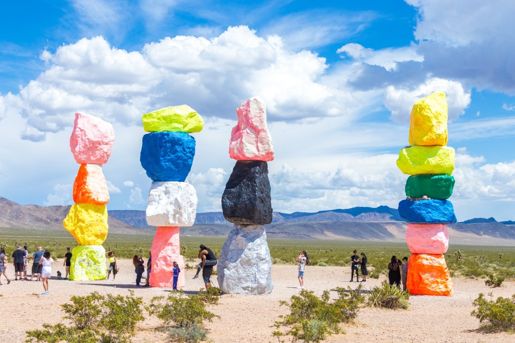 even Magic Mountains art installation near Las Vegas city. Pillars made of neon colored boulders stand against barren desert background and blue sky