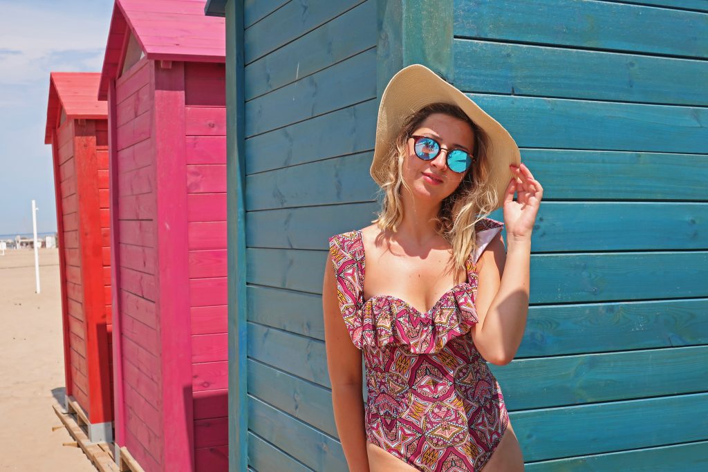 Girl at Playa de la Patacona in front of colorful dressing rooms