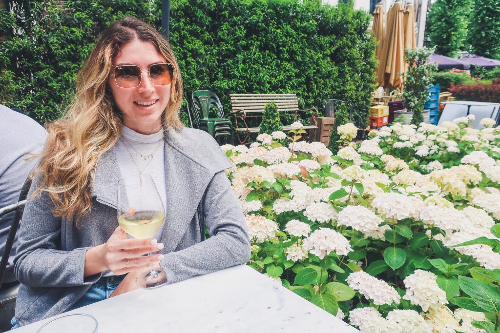 Girl holding glass of wine in the outdoor garden of Restaurant Lion Noir in Amsterdam 