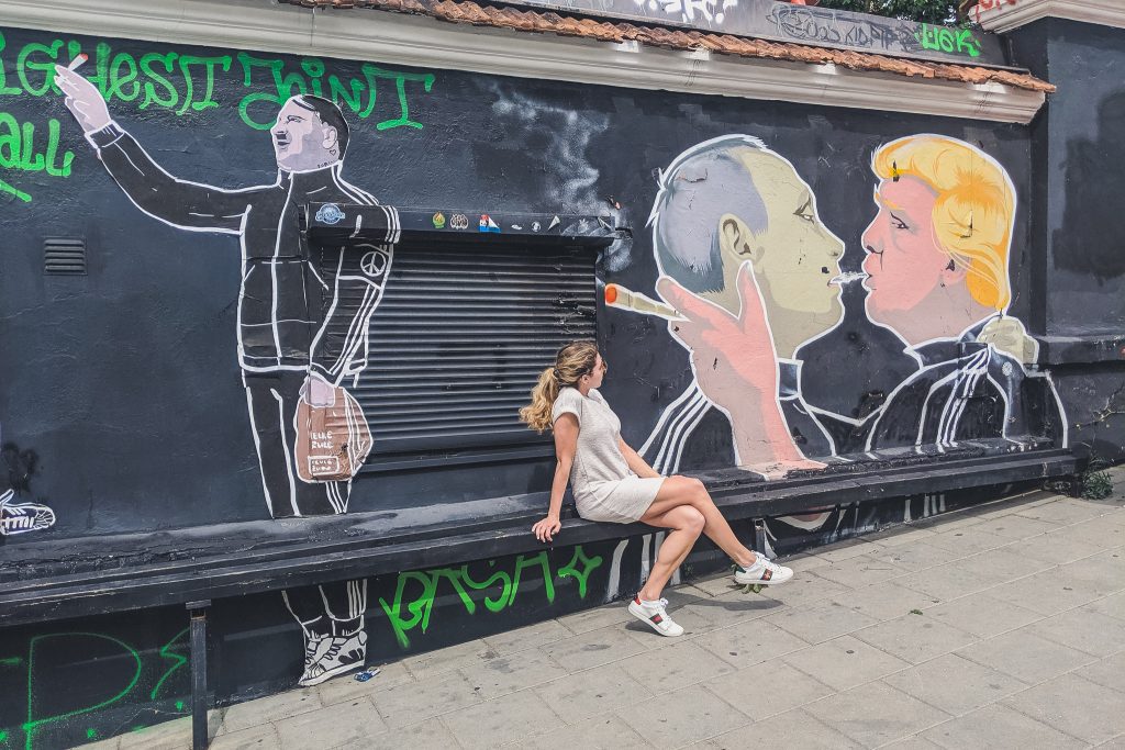 Girl sits looking at "Make Everything Great Again" Mural in Vilnius