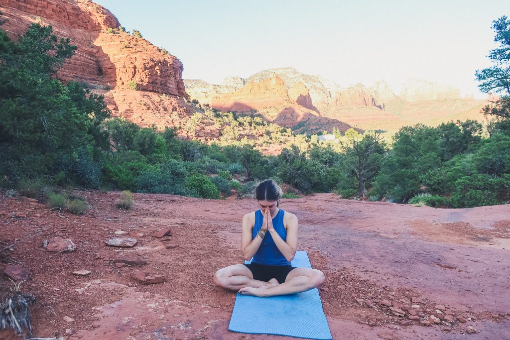 girl sits and meditates on yoga mat in Sedona, sugarloaf Trail