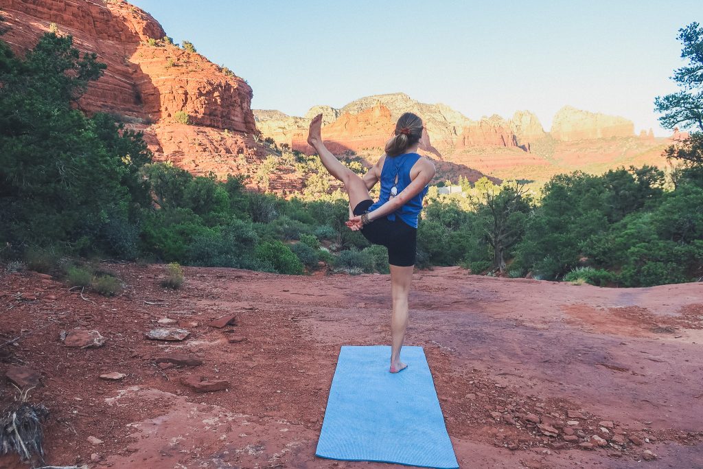 girl does yoga pose looking away from the camera, she's surrounded by nature - Red Rocks in Sedona
