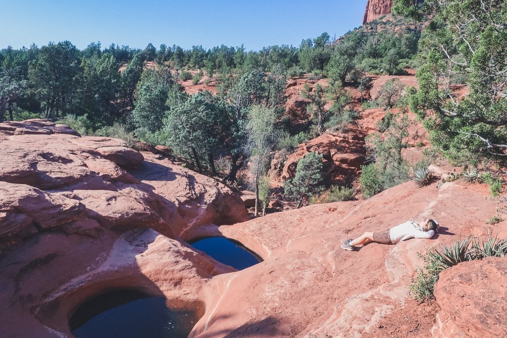 Girl lays on her back on a sandstone rock near the Seven Sacred Pools in Sedona
