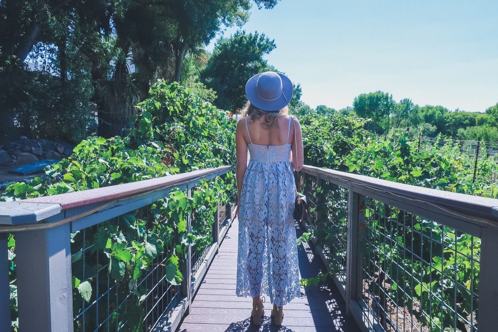 girl stands on wood bridge over vineyards in Sedona