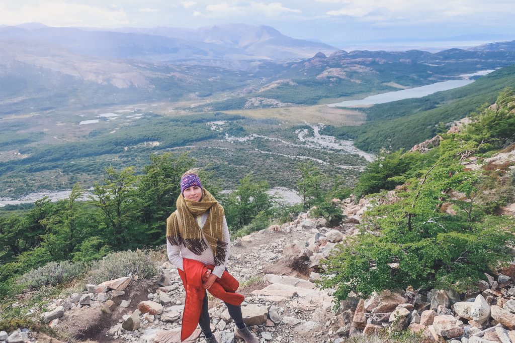 girl climbs towards laguna de los tres wearing blanket scarf