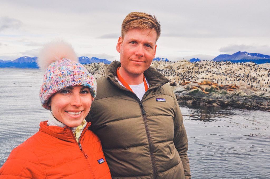 man and woman on a boat near Beagle Channel, woman wears fur pom hat