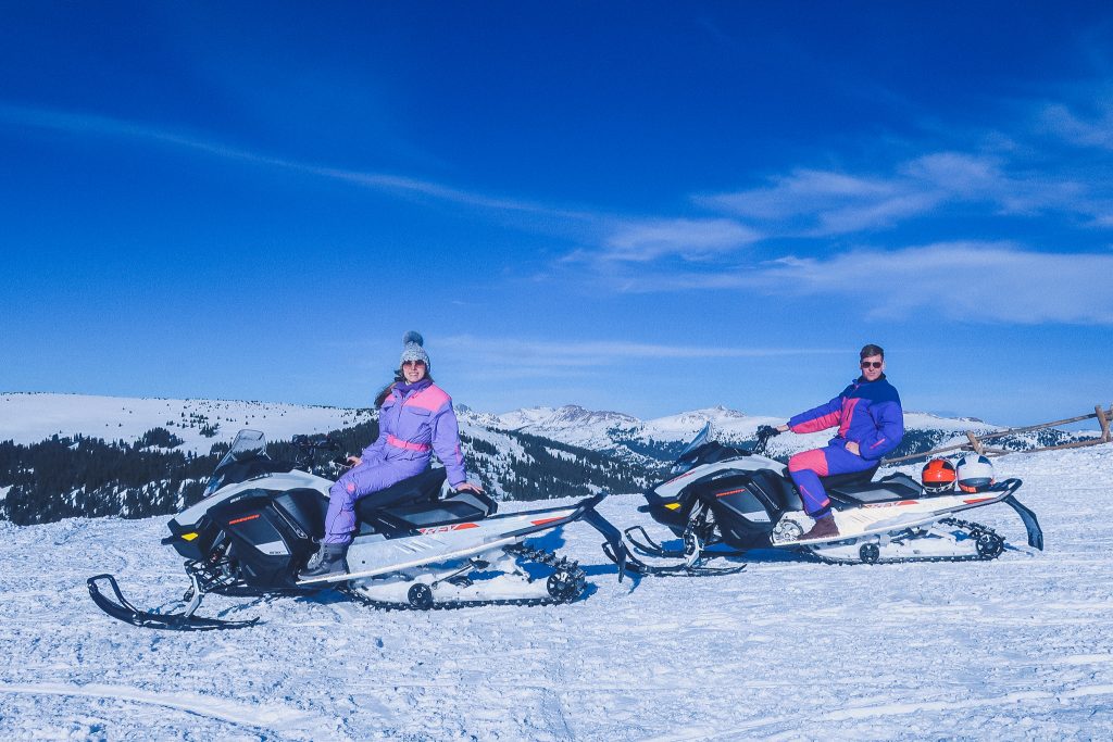 woman wears fur pom hat on snowmobile 