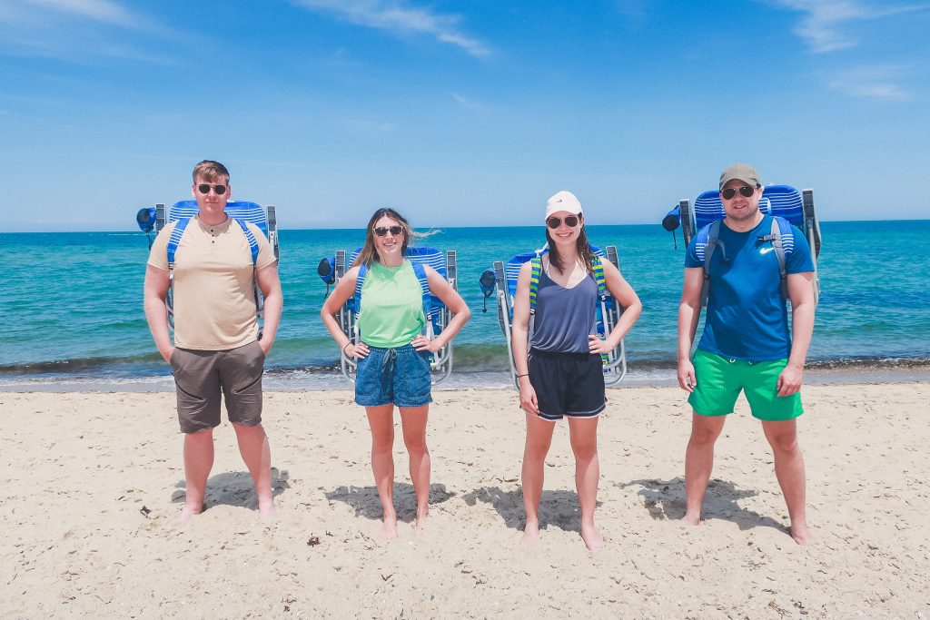 4 friends stand on beach in Nantucket with beach chair backpacks