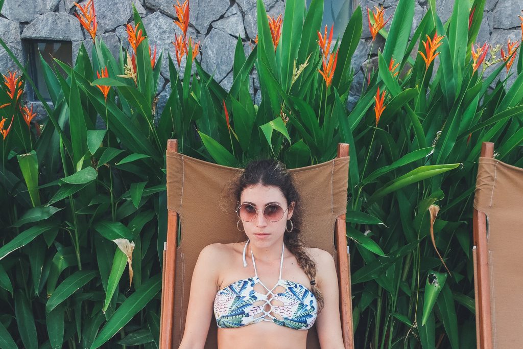 woman wears jungle print bikini top, round sunglasses and hoop earrings