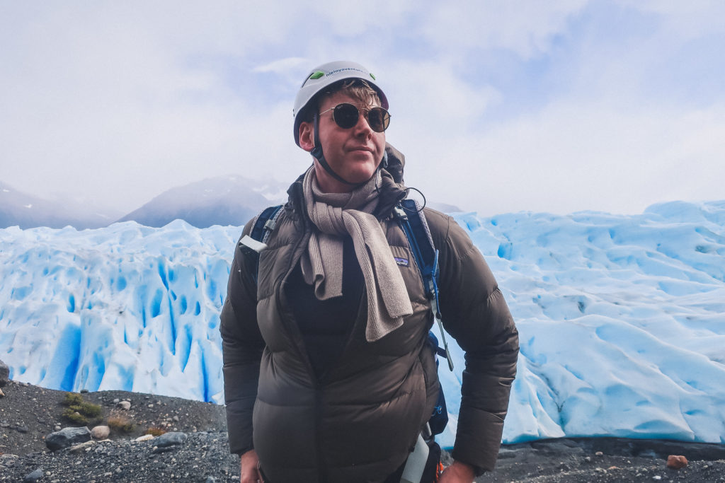 man stands in front of Perito Moreno Glacier wearing helmet, preparing for Big Ice Trek