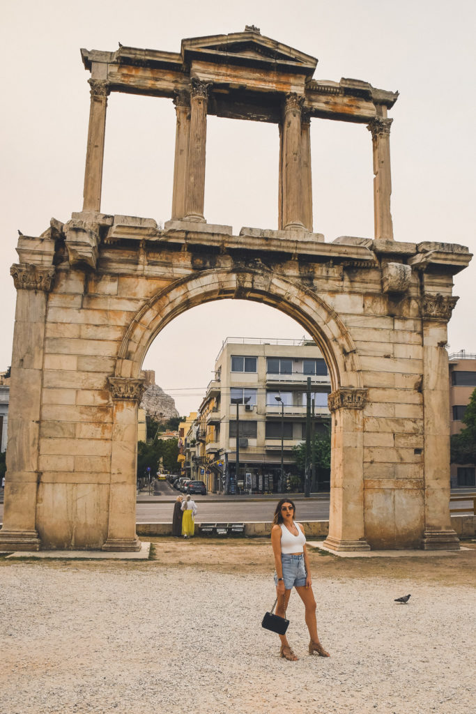 woman stands in front of Arch of Hadrian in Athens at dusk