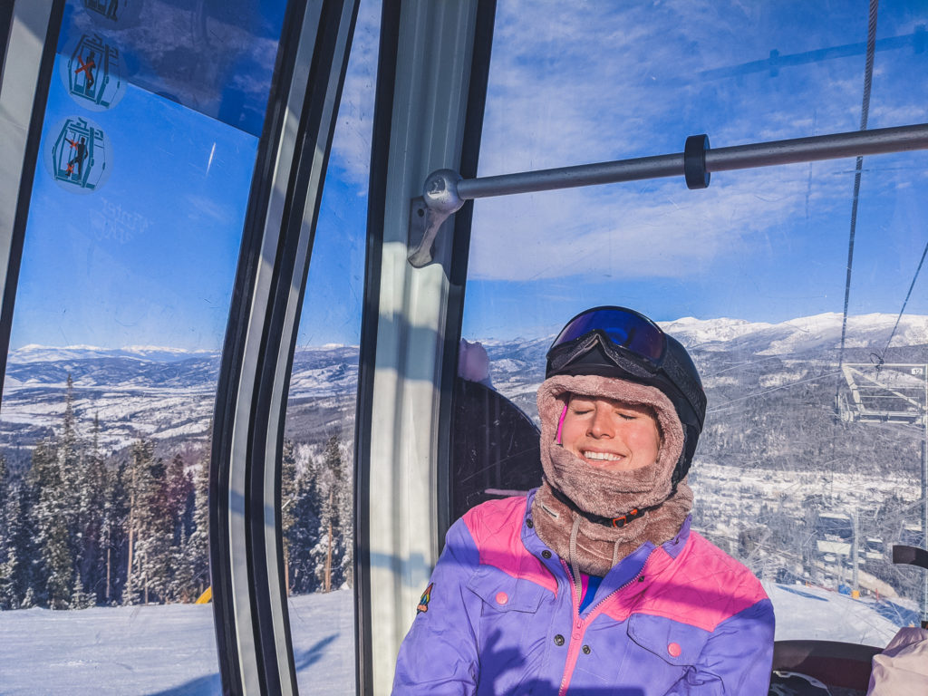 woman soaks up the sun on Winter Park Resort ski lift