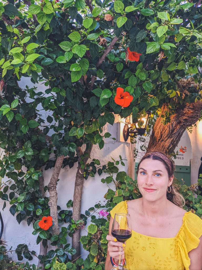 woman holding glass of rad wine, dining out in Naxos